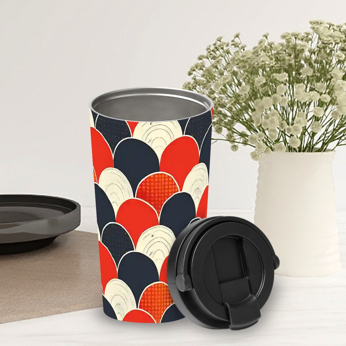 Colorful patterned travel mug with a black lid on a white surface.