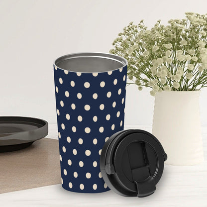 Navy blue tumbler with white polka dots on a light surface with a vase of flowers in the background.