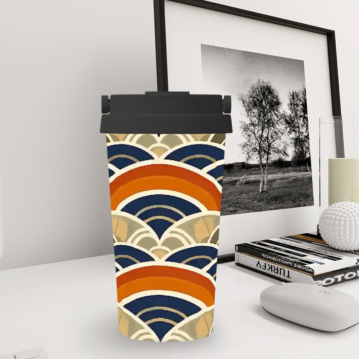 Tumbler with a colorful wave pattern on a desk with a framed picture in the background