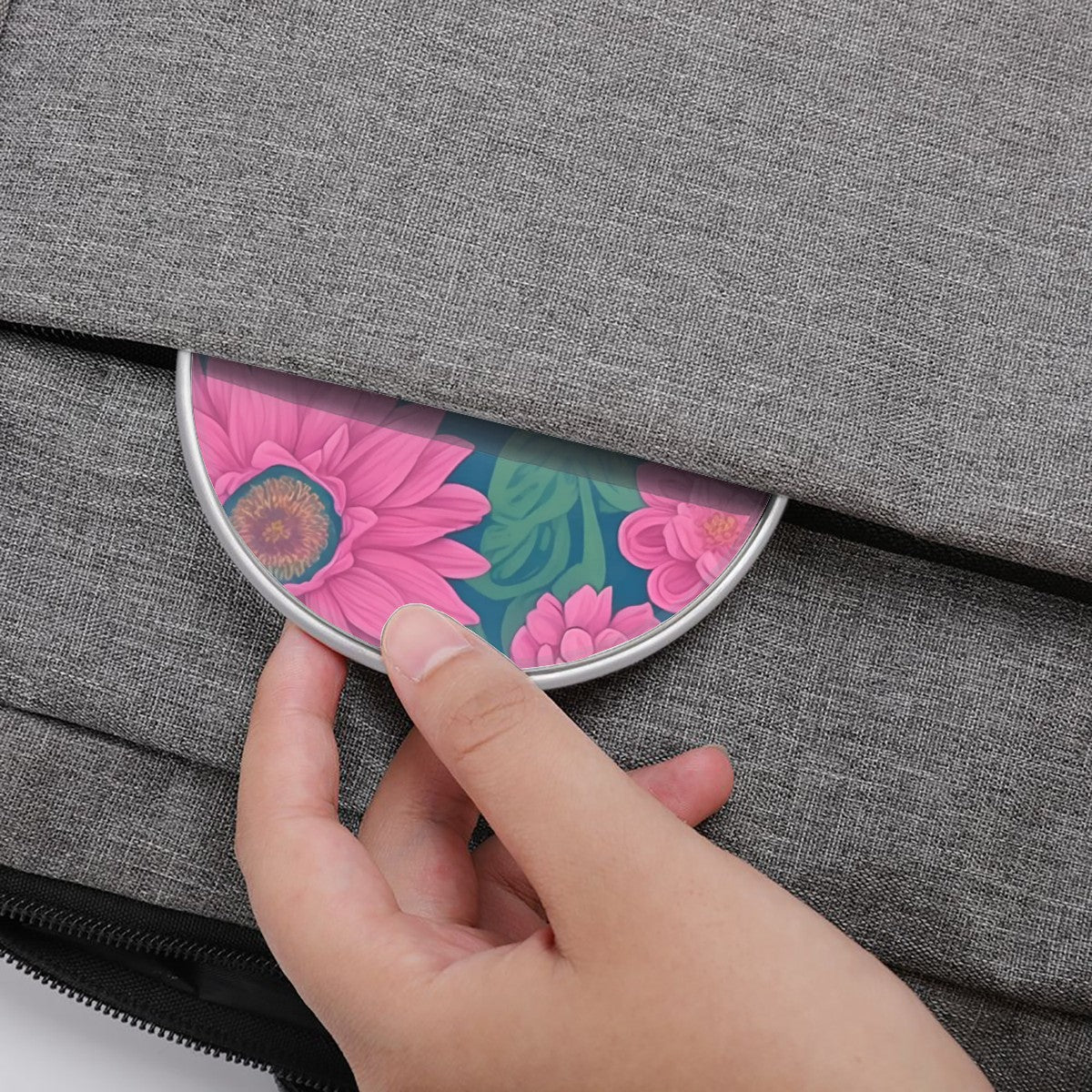 Hand placing a floral compact mirror into a gray bag