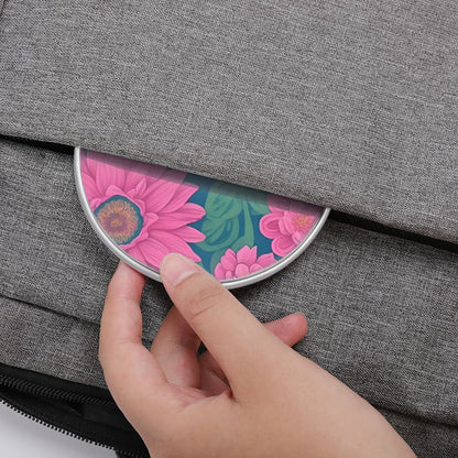 Hand placing a floral compact mirror into a gray bag